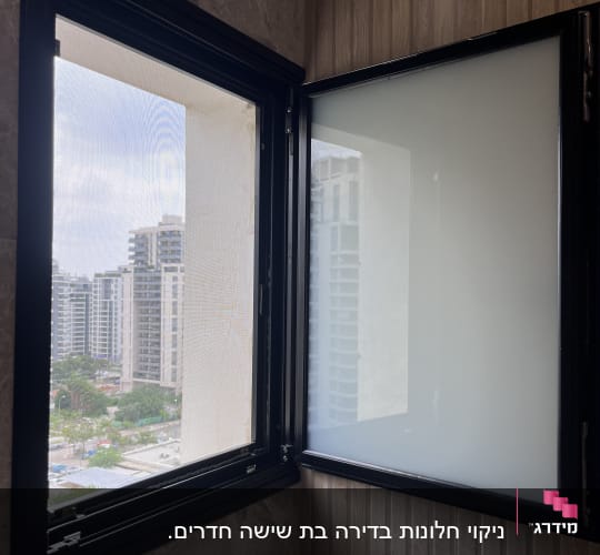 חלון פתוח עם מסגרת שחורה וקיר שיש